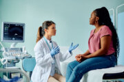 Doctor talking to Black woman during medical examination.