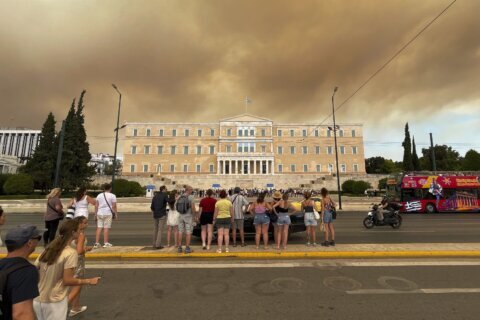 A wildfire near Greece's capital darkens the skies over Athens and advances fast