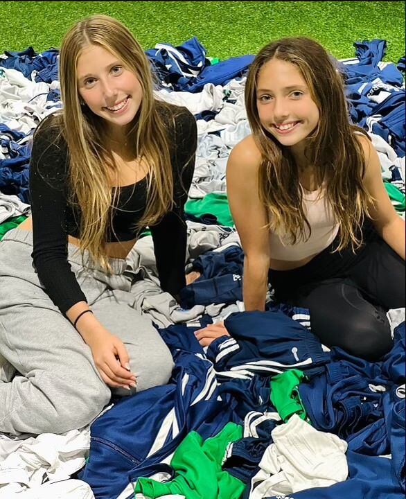 sisters sit on pile of donated jerseys