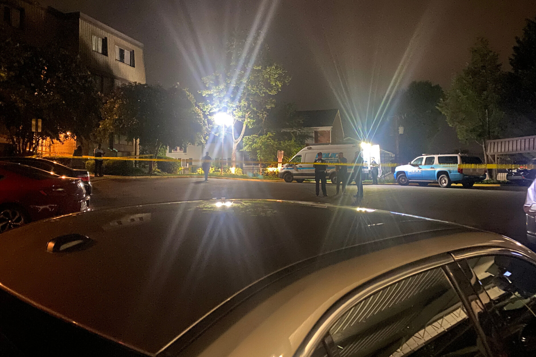 Yellow police tape and police investigators outside apartment building.