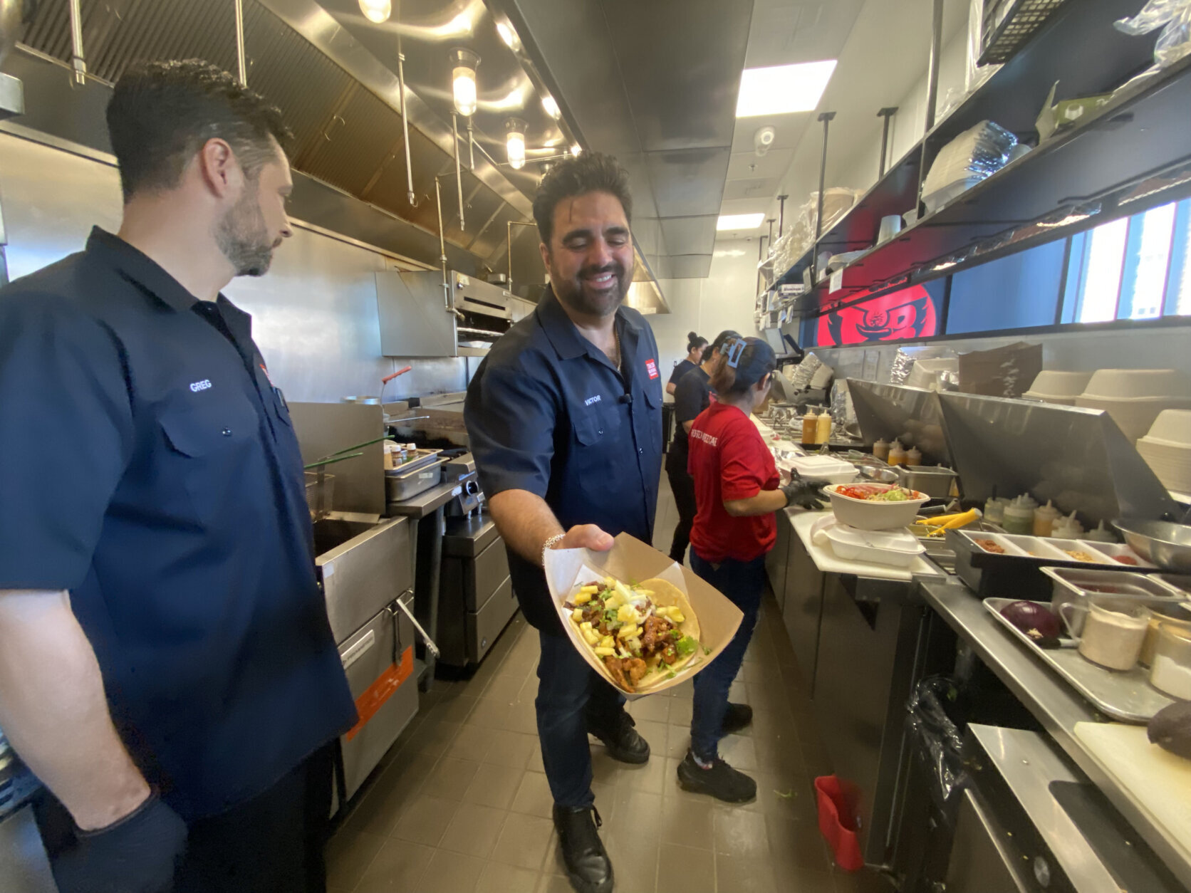 Victor Albisu in kitchen showing off a dish.