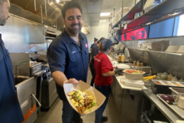 Victor Albisu in kitchen showing off a dish.