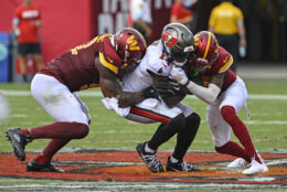 Tampa Bay Buccaneers wide receiver Chris Godwin, center, is stoped by the Washington Commanders defense during the first half of an NFL football game Sunday, Sept. 8, 2024, in Tampa, Fla. (AP Photo/Jason Behnken)