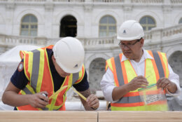 Tyler Smith, a woodcrafter with the Architect of the Capitol, and Herbert Melgar, a painter, measure out the nail placement for Congress members to hammer for the First Nail Ceremony marking the beginning of construction of the 2025 Presidential Inauguration platform at the Capitol, Wednesday, Sept. 18, 2024, in Washington. (AP Photo/Mariam Zuhaib)