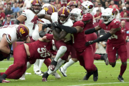 Washington Commanders running back Brian Robinson Jr., center, runs in for a touchdown as Arizona Cardinals linebacker Kyzir White (7) defends during the first half of an NFL football game, Sunday, Sept. 29, 2024, in Glendale, Ariz. (AP Photo/Rick Scuteri)