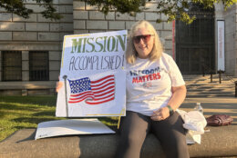 Woman with "Mission Accomplished" poster