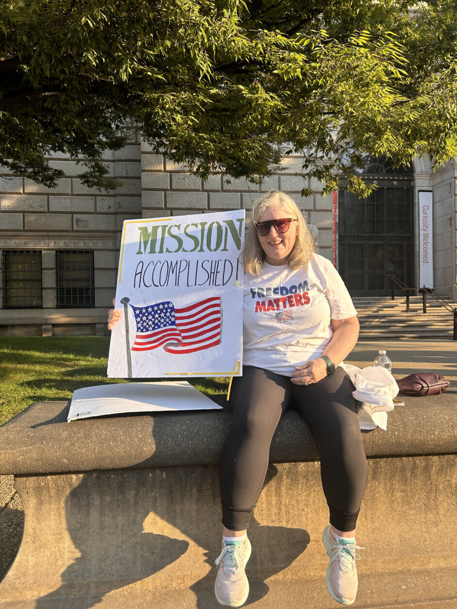 Woman with "Mission Accomplished" poster