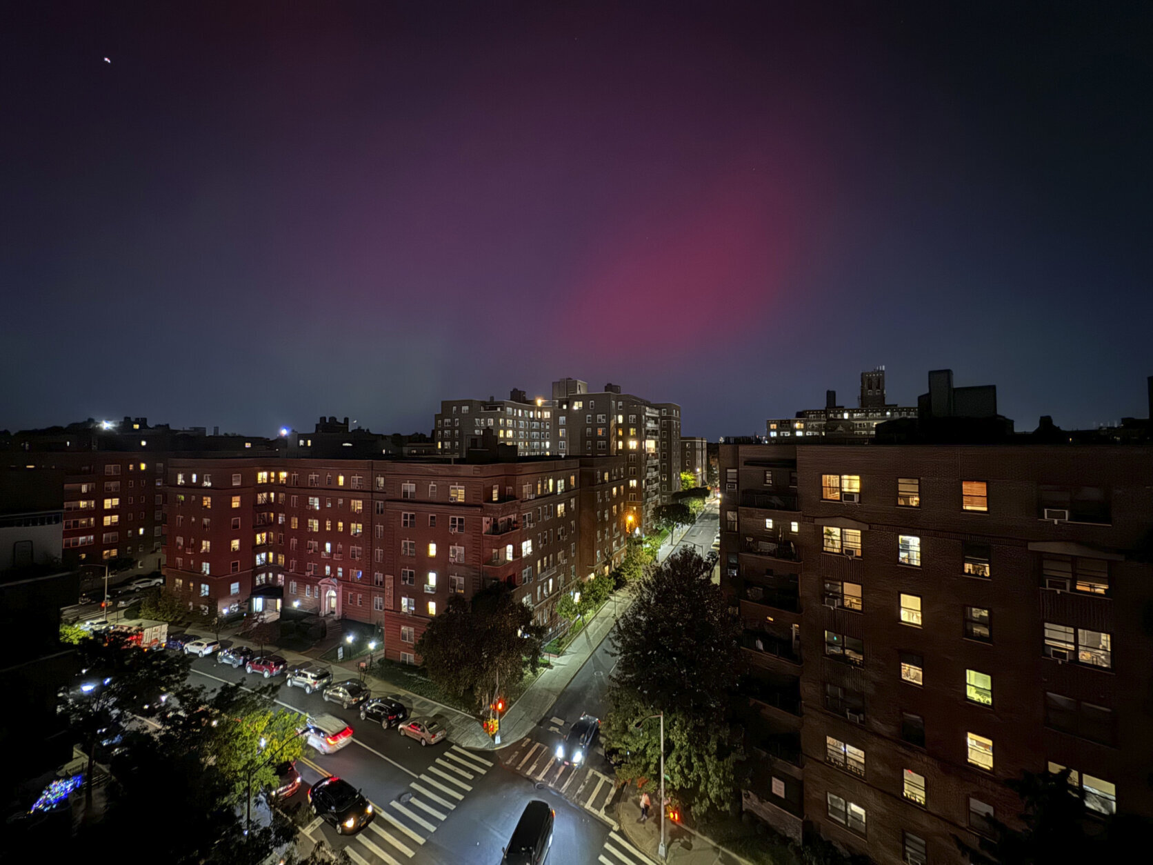 An aurora borealis, also known as the northern lights, glows in the night sky above apartment buildings in the Queens borough of New York, Thursday, Oct. 10, 2024. (AP Photo/Daniel P. Derella)