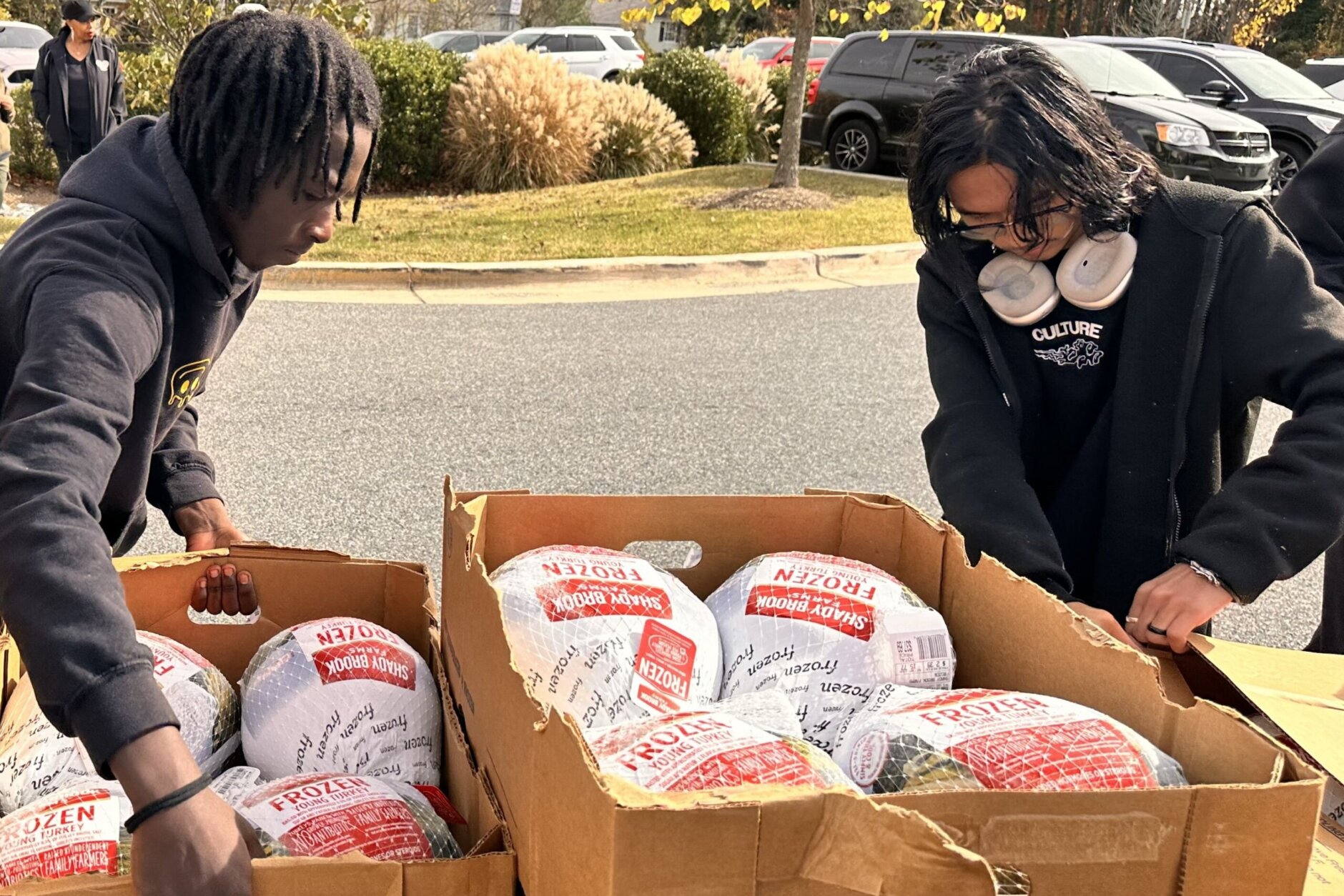 People standing over box of turkeys