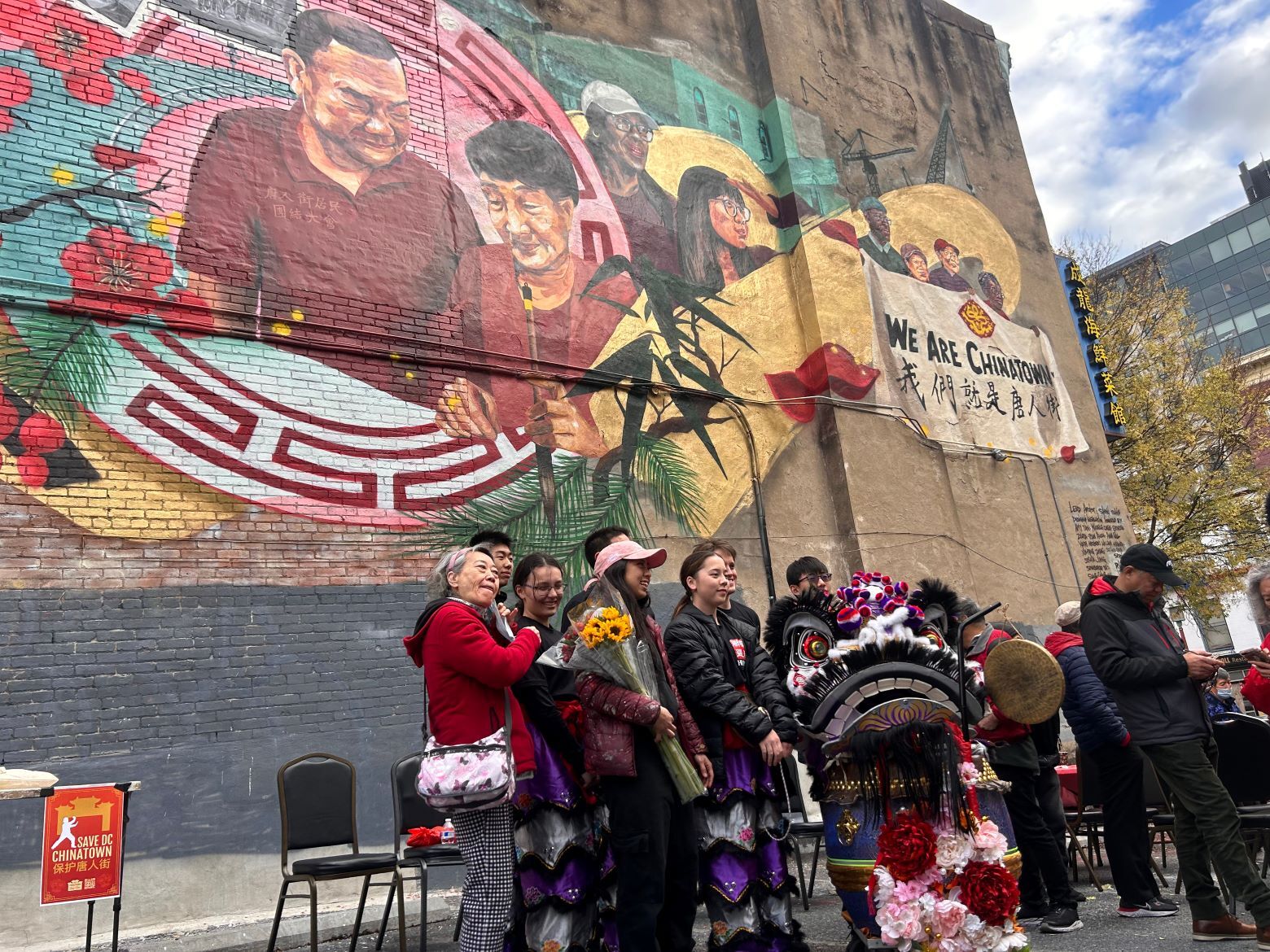 group poses for photo in front of mural