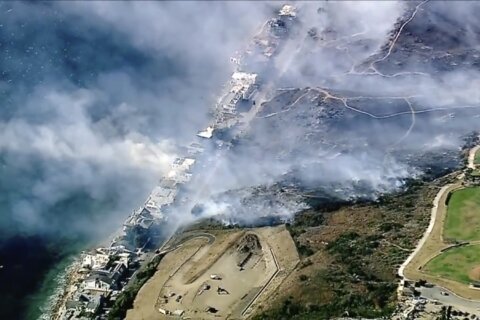 Hundreds flee and homes burn as powerful winds feed wildfires in Southern California