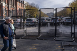 Pedestrians walk past metal security barriers on a street leading to the White House in Washington, Monday, Nov. 4, 2024, in advance of election day. (AP Photo/Ben Curtis)