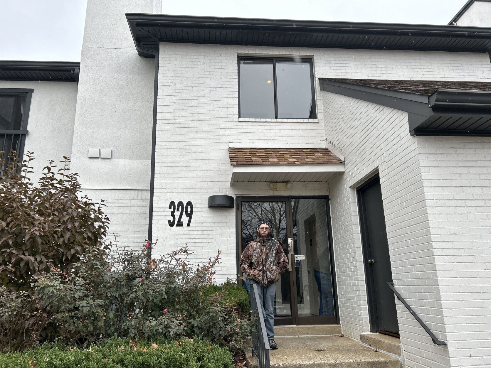 man stands outside apartment