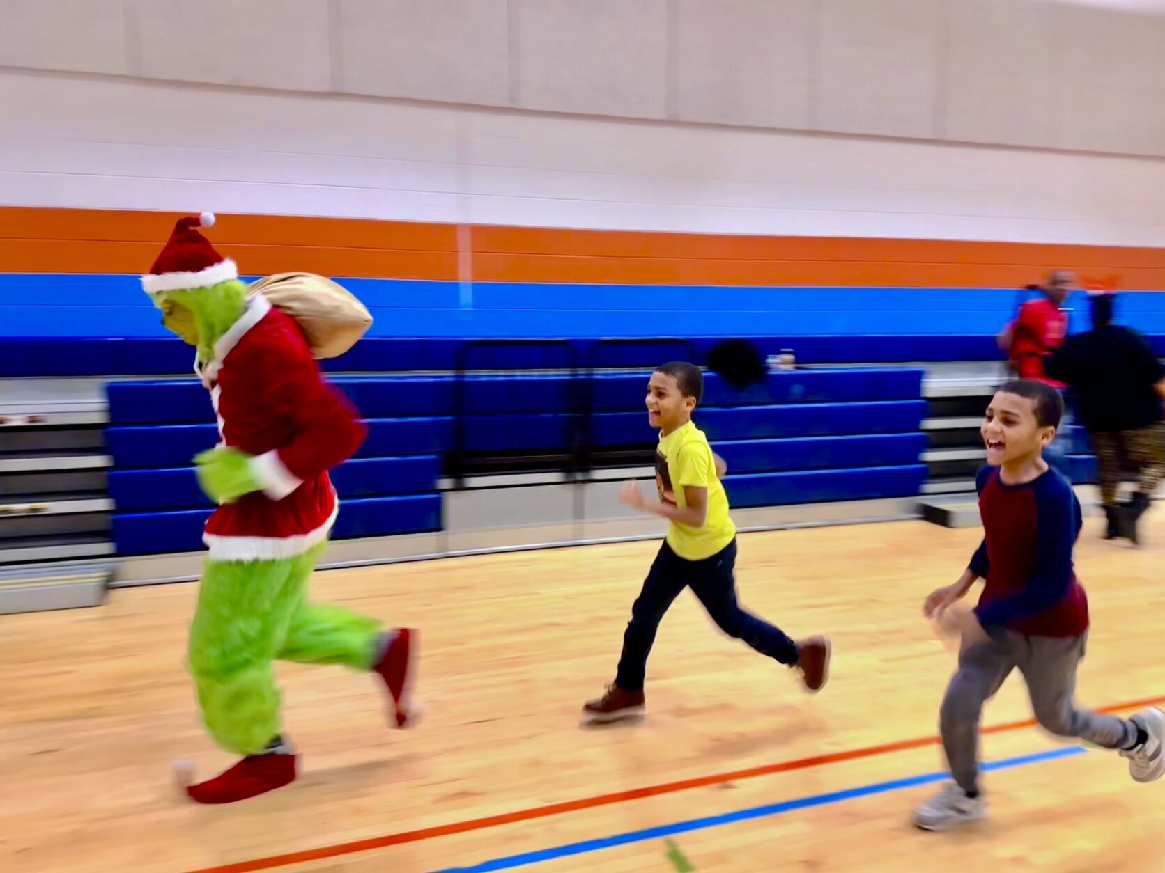 Kids running after the Grinch during the Toy Giveaway event.