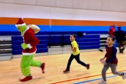 Kids running after the Grinch during the Toy Giveaway event.