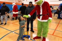 Kid high fives the Grinch during the Toy Giveaway event.