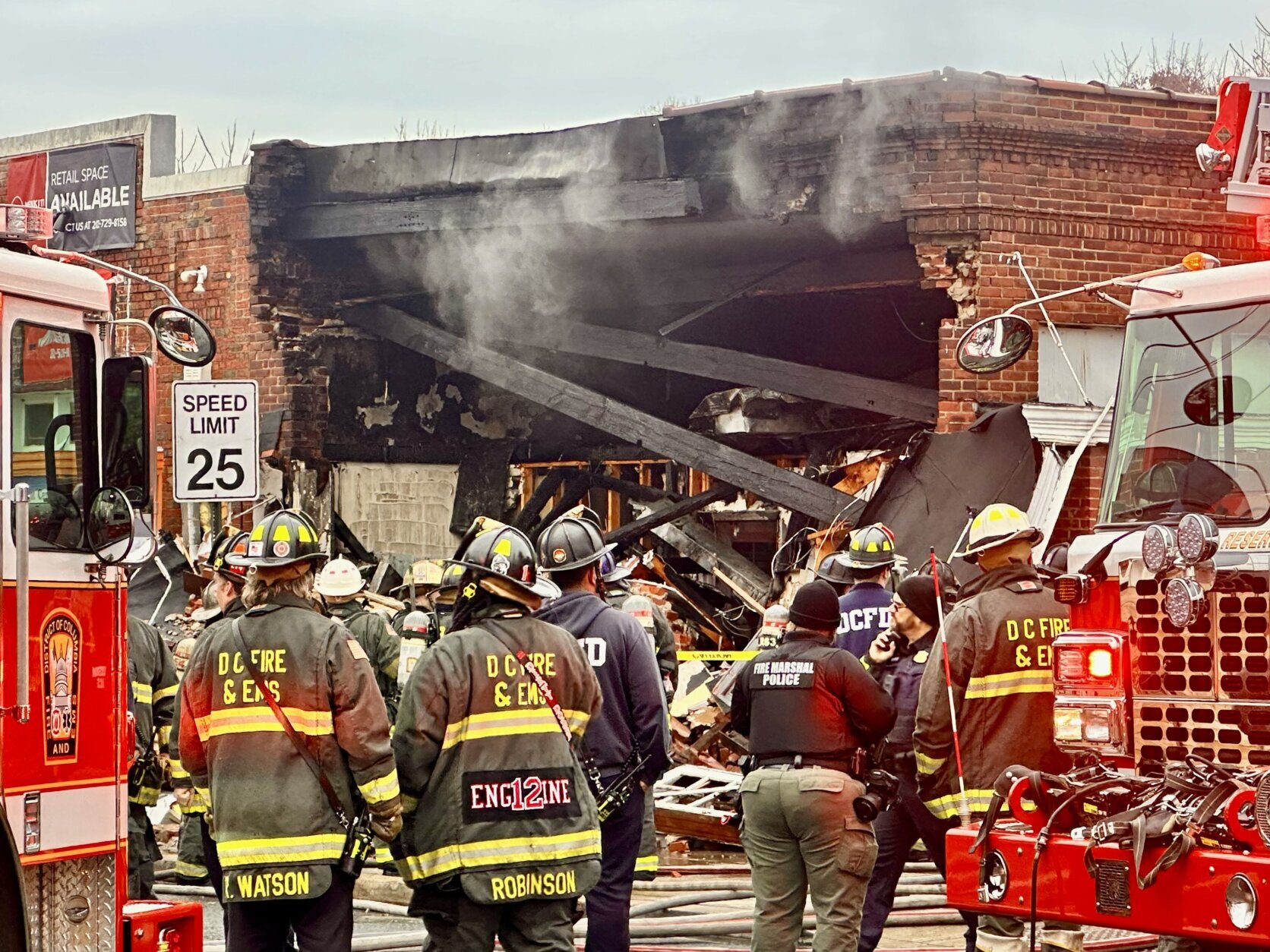 firefighters stand outside collapsed building