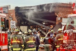 firefighters stand outside collapsed building