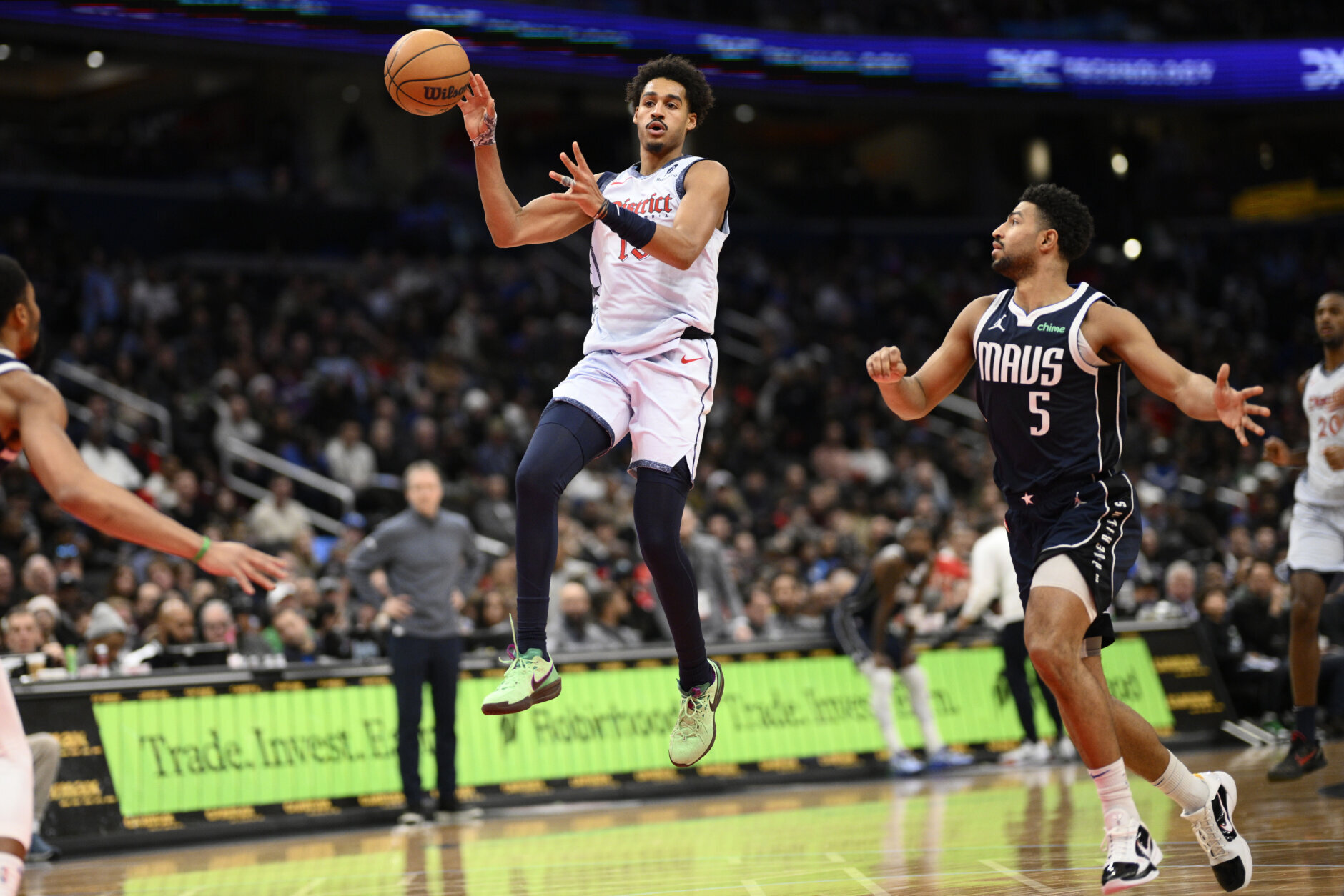 Washington Wizards guard Jordan Poole, center, passes the ball past Dallas Mavericks guard Quentin Grimes (5) during the first half of an NBA basketball game, Thursday, Dec. 5, 2024, in Washington. (AP Photo/Nick Wass)