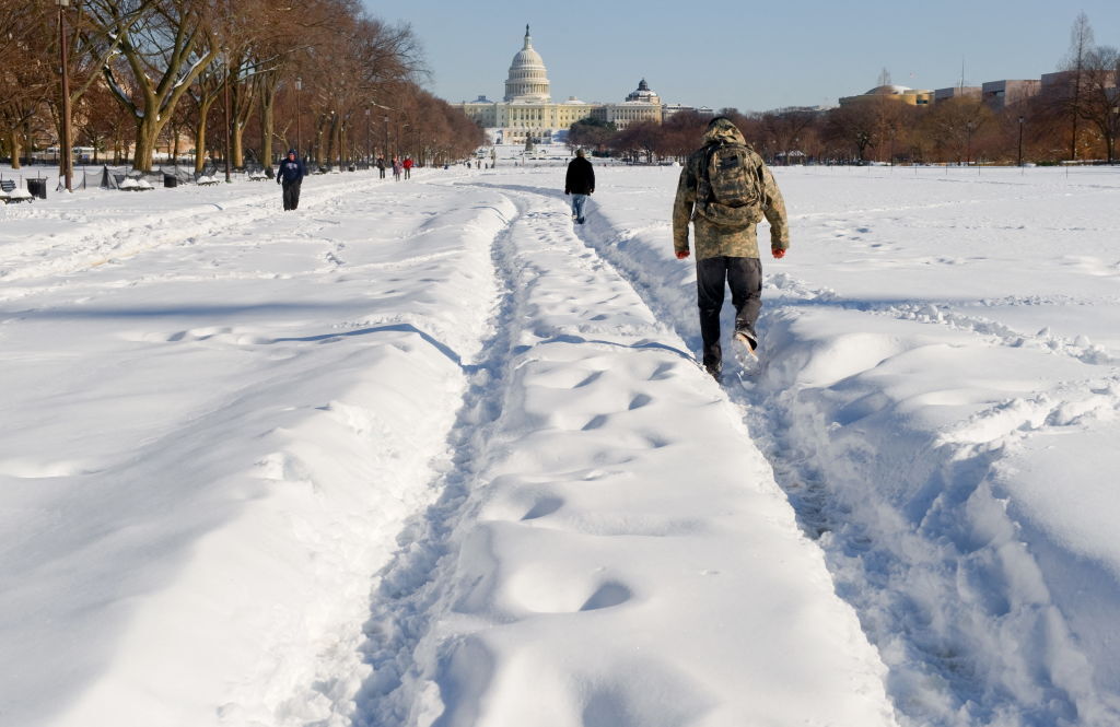 TOPSHOT - People walk through the snow-covered National Mall in Washington on December 20, 2009. A ferocious snow storm blanketed much of the eastern United States, cutting power to hundreds of thousands of homes, paralyzing air traffic and stranding motorists. The governors of Virginia, Maryland, West Virginia and Delaware declared states of emergency in advance of the storm, the worst to hit the region in decades.           AFP PHOTO/Nicholas KAMM (Photo by Nicholas KAMM / AFP) (Photo by NICHOLAS KAMM/AFP via Getty Images)