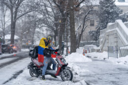 Man rides moped in snowy DC