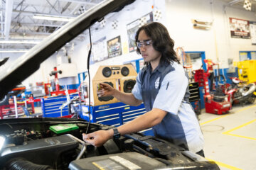 student working under the hood of a car