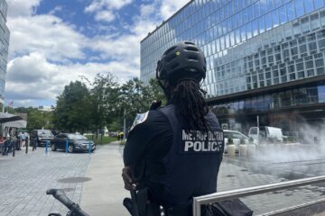 A police officer stands at The Wharf where teen violence has been increasing. (D.C. Mayor Muriel Bowser speaks at a news conference about violence from teens in the area. (WTOP/Linh Bui)