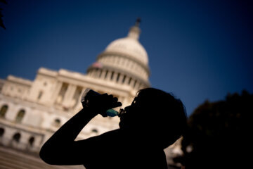 A young visitor to the U.S. Capitol Building takes a drink in the shade as much of the Northeast braces for a heat wave on June 21, 2024 in Washington, DC. Temperatures are forecasted to soar into the high 90s, with a heat index surpassing 100 degrees.