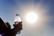 Bottle with water in a woman's hand against the bright sun