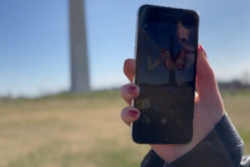 a person holds a phone near the Washington Monument