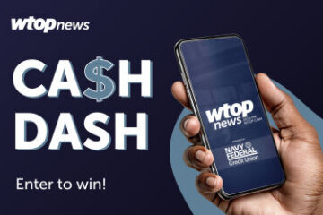 A hand holds a mobile device with the WTOP screen on it.