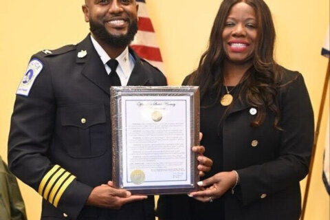 a police officer and a woman pose while holding a document