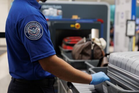 A Transportation Security Administration agent monitors travelers at the Dallas Love Field Airport on August 28, 2025. TSA agents, like other federal employees, are not paid during a government shutdown.