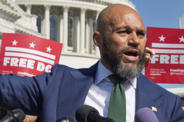 robert white speaks behind podium at rally