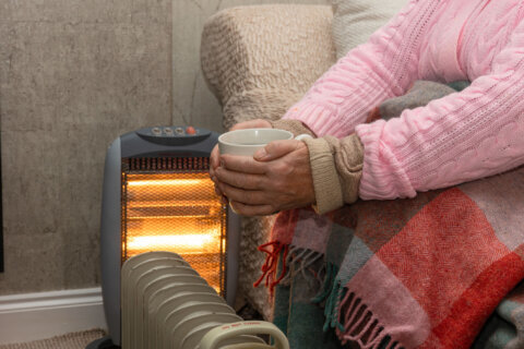 Lady keeping warm during a cold with an electric heater