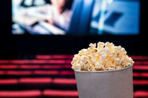 a bucket of popcorn in the foreground and empty movie theater in background