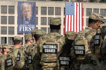 National Guard members gather near a large portrait of President Donald Trump on the Labor Department headquarters in Washington, Thursday, Jan. 8, 2026. (AP Photo/Mark Schiefelbein)