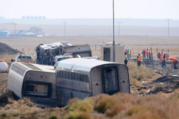 FILE - In this Sept. 27, 2021, file photo, workers stand near train tracks next to overturned cars from an Amtrak train that derailed near Joplin, Mont. (AP Photo/Ted S. Warren, File)