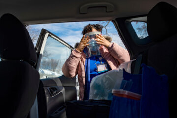 TOPSHOT - R.N Natalie O'Connor arrives at her first destination and prepares for the visit by putting on PPE including a face shield in Manchester, Connecticut on February 12, 2021. - Mobile vaccinations are being done by nurses visiting patients who are home bound or can't reach a Covid-19 vaccine site due to health or mobility reasons. Hartford HealthCare at Home is trying to vaccinate 3,355 patients with a team of almost 90 nurses. Nurses are sent out with pre-loaded Covid-19 vaccine doses and have a few hours to get to as many homes as they can before the vaccine spoils in the car.  Doses are good for six hours once in the syringe. (Photo by Joseph Prezioso / AFP) (Photo by JOSEPH PREZIOSO/AFP via Getty Images)