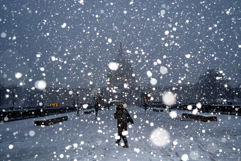 snow falls at night with capitol building in background