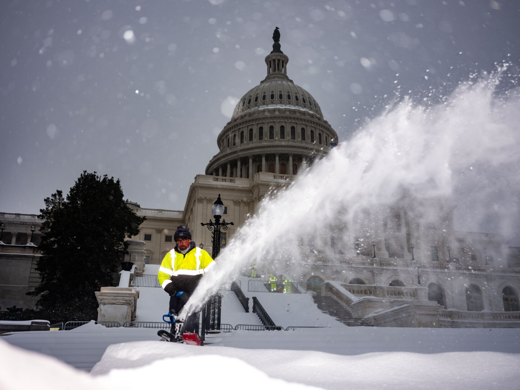 worker uses mini snow plow in front of us capitol