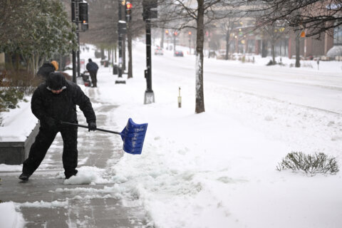 man shovels snow on sidewalk