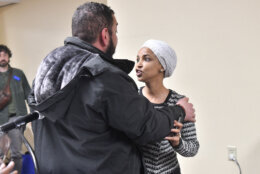 US Representative Ilhan Omar (D-MN) (R) reacts after being sprayed with an unknown substance by a man as she hosted a town hall in Minneapolis, Minnesota, on January 27, 2026. US Democratic congresswoman Ilhan Omar was targeted during a speech late on January 27 by a man who sprayed an unidentified liquid at her from a syringe before being tackled by security guards, according to an AFP journalist at the scene. The man was led out of the premises as Omar, a frequent target of attacks by President Donald Trump, continued her speech saying "we will stay resilient in the face of whatever they might throw on us." (Photo by Octavio JONES / AFP via Getty Images)