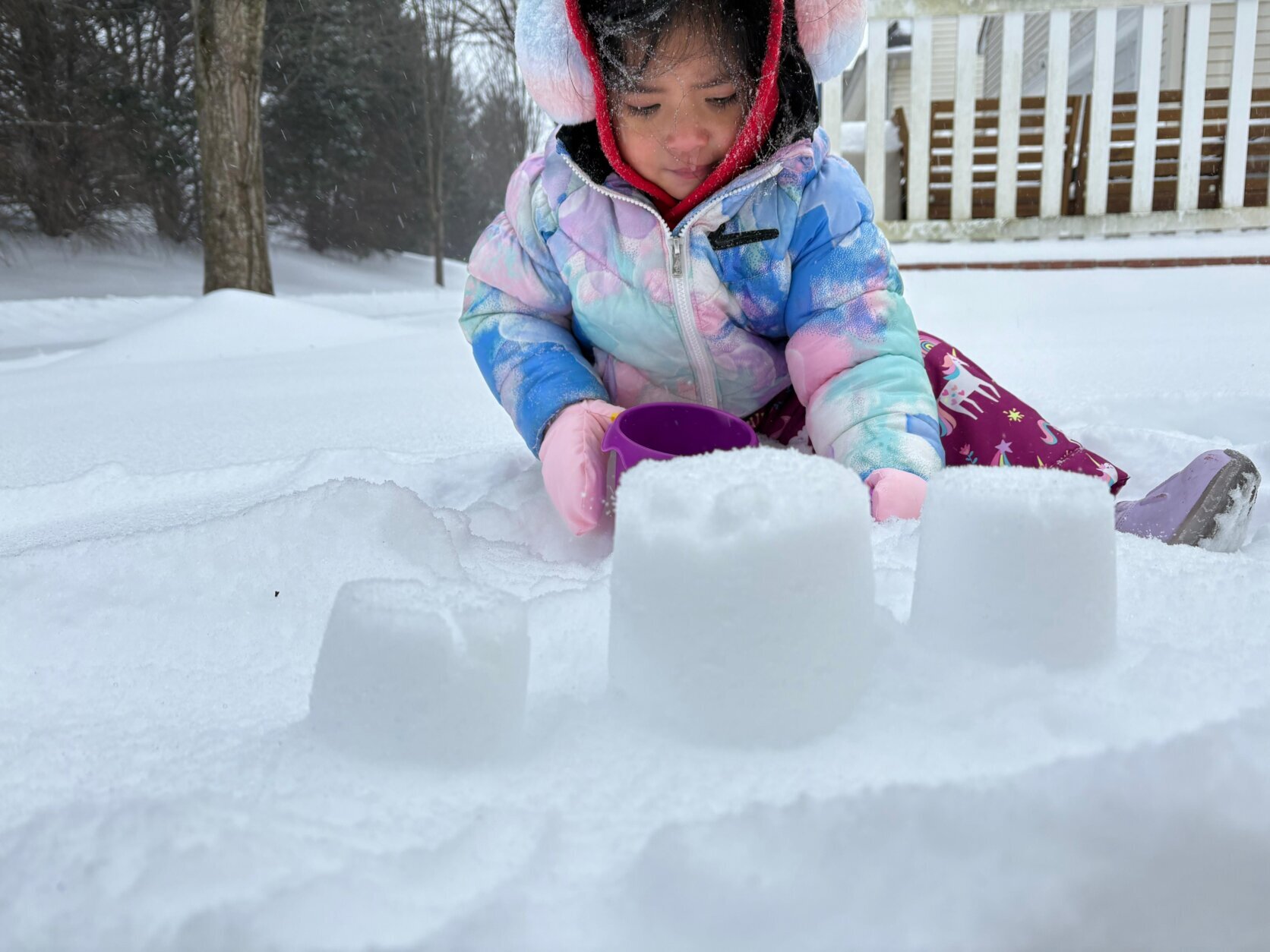 little girl builds castle in snow