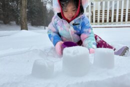 little girl builds castle in snow