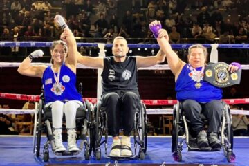 boxers in wheel chair have arms raised as victors in the ring