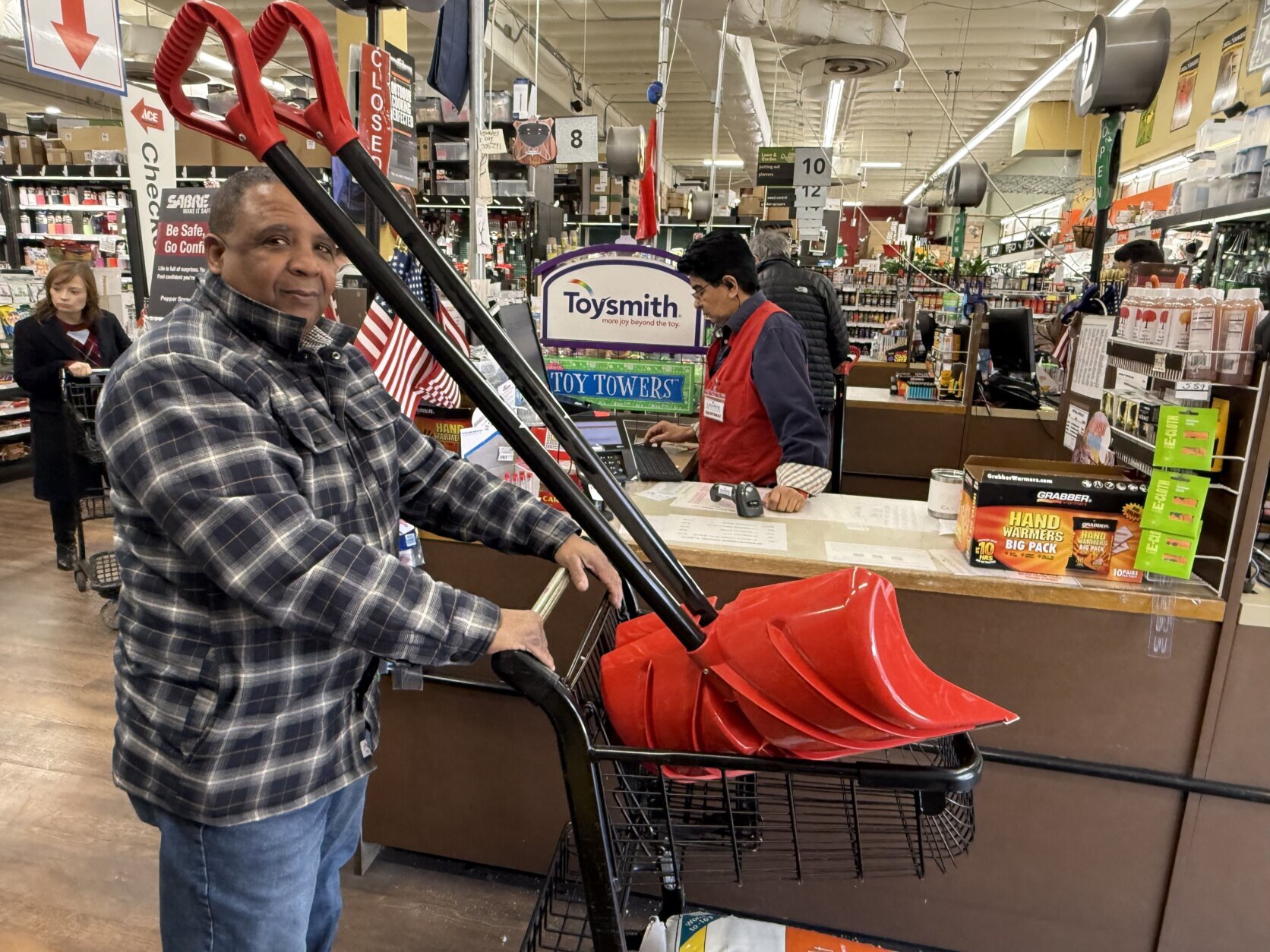 man with two shovels in shopping cart checks out at store