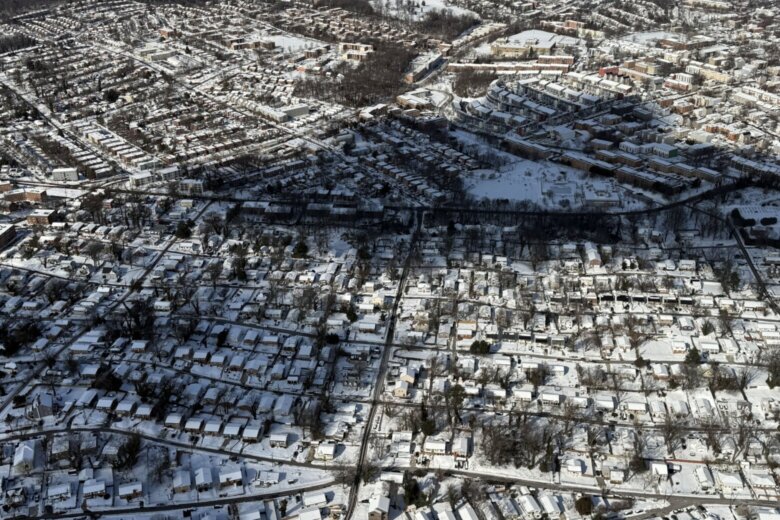 aerial view of suburban neighborhood with many houses and snow on the ground