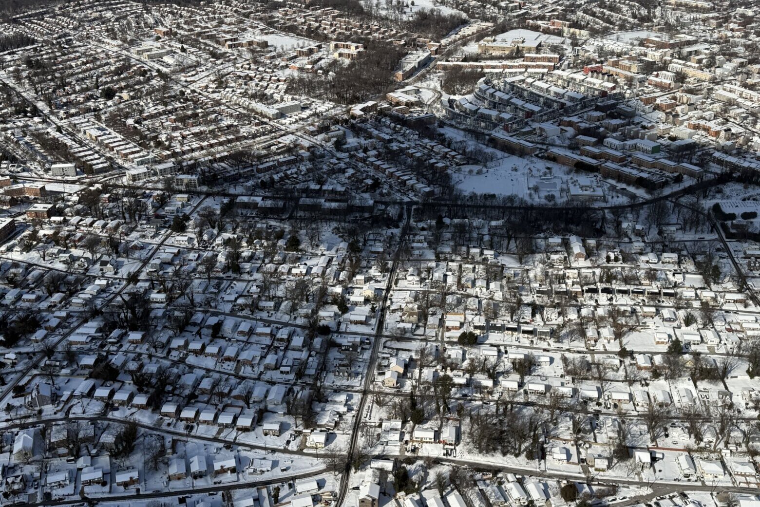 aerial view of suburban neighborhood with many houses and snow on the ground
