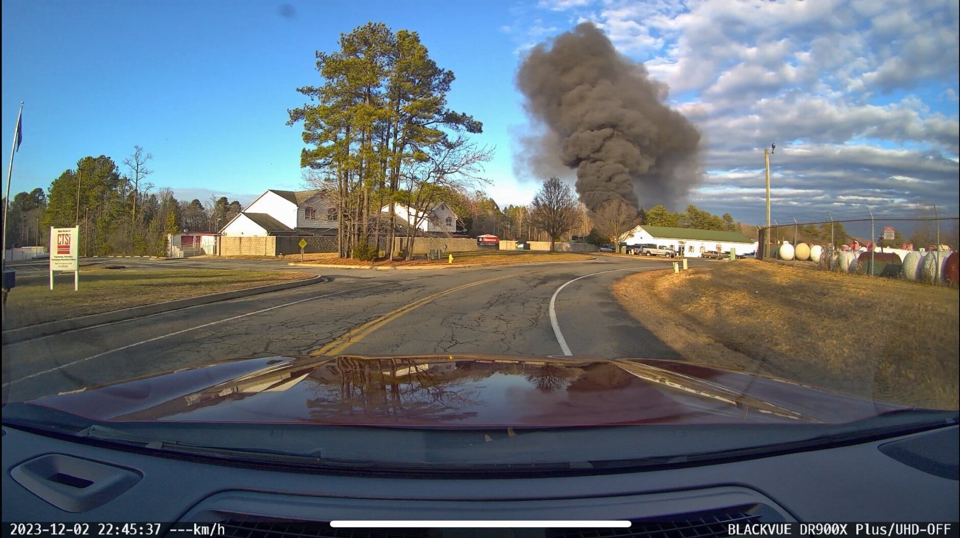 view from car through windshield of smoke billowing into sky from fire